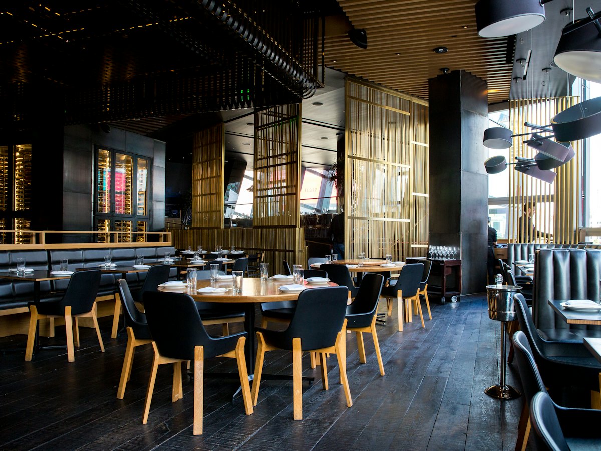 A dim restaurant dining room with wooden tables set for service